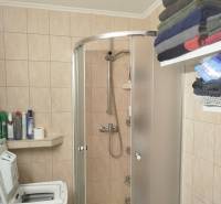 Fürdőszoba a garzonlakásban mosógéppel, zuhanyzóval, polccal és elhelyezett törölközőkkel.