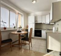 Konyha egy egyszobás lakásban, kerek asztallal és fa dekorációjú padlóval.