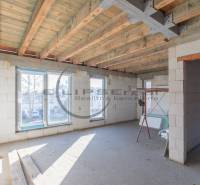 Egy építés alatt álló épület belső tere fa mennyezettel és nagy ablakokkal.