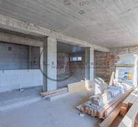 Egy építés alatt álló épület belső tere egyenetlen téglafallal és építőanyaggal a padlón.