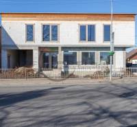 Egy befejezetlen homlokzatú épület Nagylévárdon, az út mellett áll.