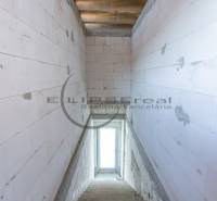 Kilátás egy lépcsőházra egy épületben betonfalakkal és egy ablakkal a végén.