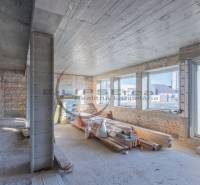 Az épület belső tere téglafalakkal, nagy ablakokkal és építőanyaggal.