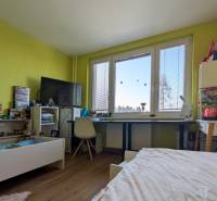 Gyerekszoba egy háromszobás lakásban, fa dekoros padlóval és élénkzöld falakkal.