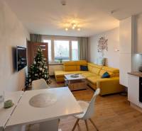 Nappali egy háromszobás lakásban, fa dekorációjú padlóval és karácsonyfával.