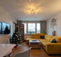 Nappali egy háromszobás lakásban sárga kanapéval és fa dekorációjú padlóval.