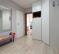 A háromszobás lakás előszobája nagy tükörrel, paddal és fa dekorációjú padlóval.