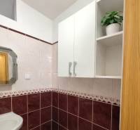 Fürdőszoba egy kétszobás lakásban kerámia burkolattal és tükörrel a mosdó felett.