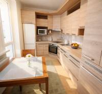 Konyha egy kétszobás lakásban fa dekorációval, étkezőasztallal és modern készülékekkel.