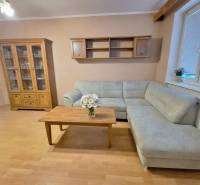 Nappali egy kétszobás lakásban sarokkanapéval, a fa dekoráció kiegészíti a belső teret.