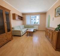 Nappali egy kétszobás lakásban kanapéval, bútorokkal és fa dekorációjú padlóval.