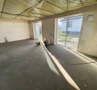 Üres szoba nagy ablakokkal egy családi házban, padlóburkolat nélkül.