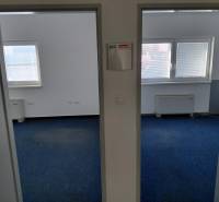 Irodák belső tere kék szőnyeggel és redőnyös ablakokkal.