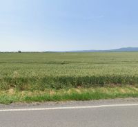 Mezőgazdasági és erdőterületek Budmericen kiterjedt mezőkkel és távoli dombokkal.