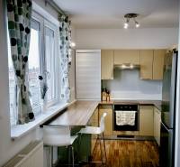 Konyha egy 3 szobás lakásban bárpulttal, fa hatású padlóval és nagy ablakkal.