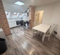 Egy egyszobás lakás belső tere fa dekoros padlóval és téglaburkolatú konyhával.