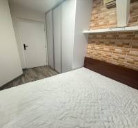 Hálószoba tégladekorációval egy egyszobás lakásban, a padlón fa hatású padlóburkolat.