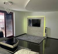 Nappali egy családi házban fényes padlóval és falra szerelt TV-vel.