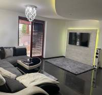 Nappali egy családi házban kanapéval és televízióval a kőburkolatú falon.