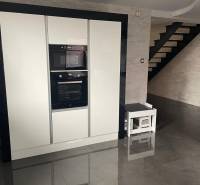 Konyha egy családi házban fényes fekete padlóval és fehér készülékekkel.