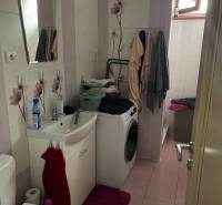 Fürdőszoba családi házban szaniterekkel, mosógéppel és virágos csempével.