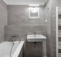 Fürdőszoba egy kétszobás lakásban káddal, mosdóval és létrás radiátorral.