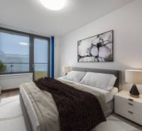 Hálószoba egy kétszobás lakásban kényelmes ággyal, képpel és lámpával az éjjeliszekrényen.