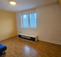 Szoba kék kanapéval, fa dekorációjú padlóval és fehér bútorokkal egy háromszobás lakásban.