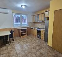 Konyha egy háromszobás lakásban konyhabútorral, étkezőasztallal és csempével.