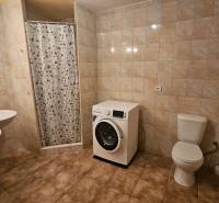 Fürdőszoba egy háromszobás lakásban zuhanyzóval, dupla mosdóval, WC-vel és mosógéppel.