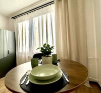 Egy egy szobás lakás egyik otthonos sarka kerek asztallal és edényekkel.