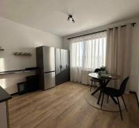 Konyha fa mintázatú padlóval és asztallal egy egyszobás lakásban.