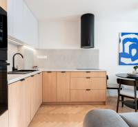 Konyha fa mintázatú padlóval, fa szekrényekkel és étkezőasztallal egy háromszobás lakásban.