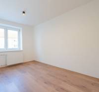 Világos szoba fa dekorációjú padlóval egy háromszobás lakásban, ablakkal szembeni lámpával.