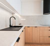 Konyhapult egy háromszobás lakásban, fa mintázatú padlóval és fekete mosogatóval.