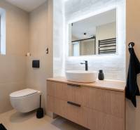 Fürdőszoba egy háromszobás lakásban mosdóval, tükörrel és fali WC-vel.