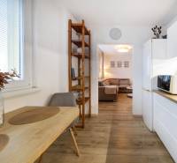 Konyha egy kétszobás lakásban étkezőasztallal, polccal és fa dekorációjú padlóval.