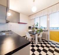 Konyha egy háromszobás lakásban fekete-fehér csempével, étkezőasztallal és nagy ablakokkal.