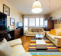 Nappali egy háromszobás lakásban bőr kanapékkal és fa dekoros padlóval.