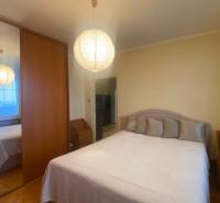 Hálószoba egy háromszobás lakásban szekrénnyel, ággyal és fa dekorációjú padlóval.