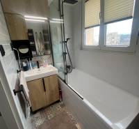 Fürdőszoba egy négy szobás lakásban káddal, mosdóval, tükörrel és színes csempével.