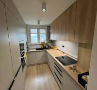 Konyha egy 4 szobás lakásban, konyhabútorral, háztartási gépekkel és fa dekorációjú padlóval.