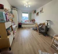 Gyerekszoba egy négy szobás lakásban, fa dekoros padlóval, játékokkal és ággyal.