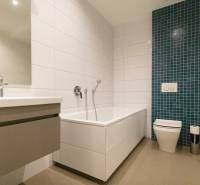 Fürdőszoba egy kétszobás lakásban káddal, mosdóval és zöld csempés panellel.