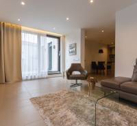 Nappali egy kétszobás lakásban kényelmes kanapéval, fotellel és üvegasztallal.