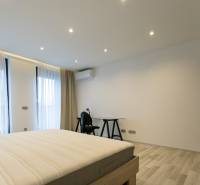 Hálószoba egy kétszobás lakásban ággyal, asztallal és fa dekorációjú padlóval.