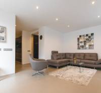 Nappali egy kétszobás lakásban kanapéval, fotellel, szőnyeggel és képekkel a falon.