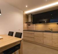 Két szobás lakás konyhája minimalista dizájnnal, fa dekorációval és étkezőasztallal.