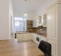 Konyha egy háromszobás lakásban, fa dekor padlóval és klasszikus konyhaszekrényekkel.