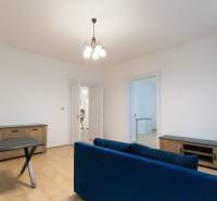 Nappali egy háromszobás lakásban, fa dekorációjú padlóval és kék kanapéval.